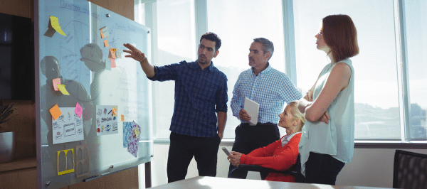 a group of people standing indoors, looking at a poster on a wall.